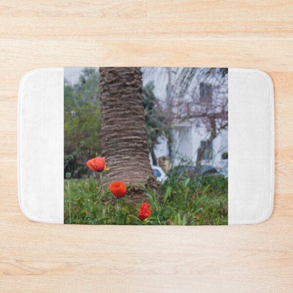 Item preview, Red Poppies Blooming In An Urban Garden Next To A Palm Tree Trunk On A Spring Day designed and sold by Nmallia.