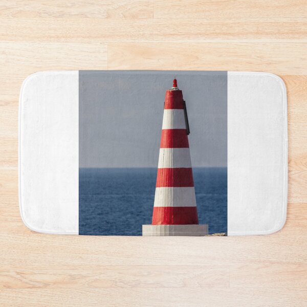 Item preview, Red and White Striped Coastal Beacon On Rocky Shore With Calm Blue Sea and Sky designed and sold by Nmallia.