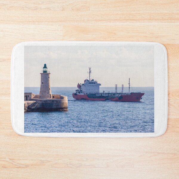 Item preview, Lighthouse Guarding Harbor Entrance as Cargo Ship Passes Along Coastal Waters at Sea designed and sold by Nmallia.