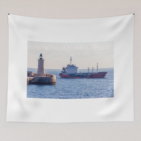 Item preview, Lighthouse Guarding Harbor Entrance as Cargo Ship Passes Along Coastal Waters at Sea designed and sold by Nmallia.