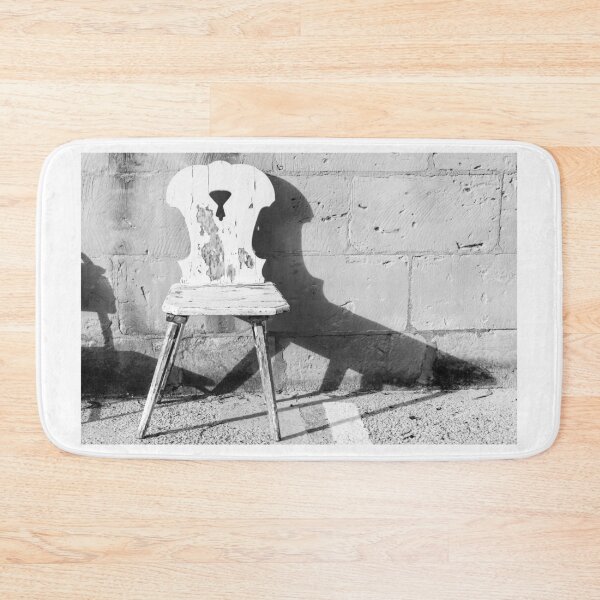 Item preview, Vintage Weathered Wooden Chair Casting Shadow Against Textured Stone Wall in Minimal Black and White designed and sold by Nmallia.