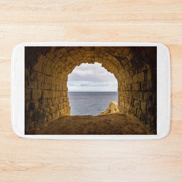 Item preview, Stone Arch Tunnel Framing A Calm Ocean View Over Rocky Coastal Cliff In Golden Light designed and sold by Nmallia.