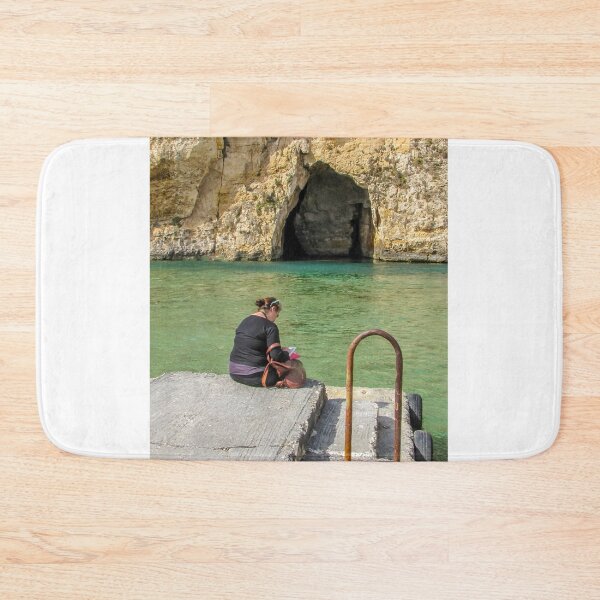 Item preview, Woman Reading On A Pier By Turquoise Water Near A Rocky Sea Cave And Sunlit Cliff designed and sold by Nmallia.