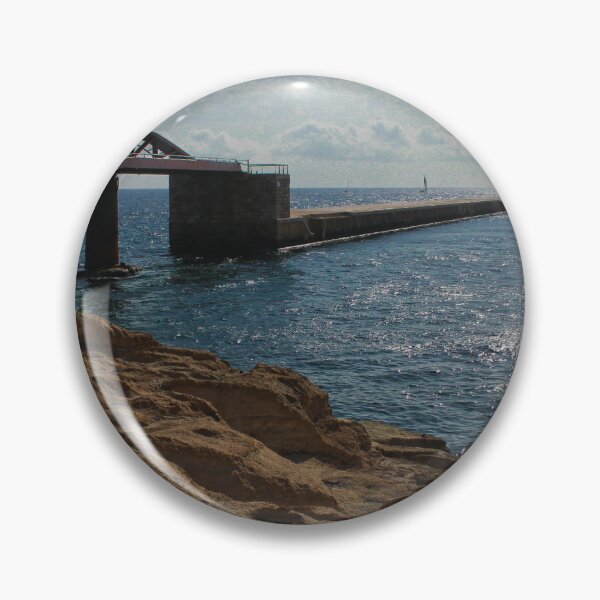 Item preview, Sunlit Rocky Coastline With Arched Bridge and Distant Lighthouse Over Sparkling Blue Sea designed and sold by Nmallia.