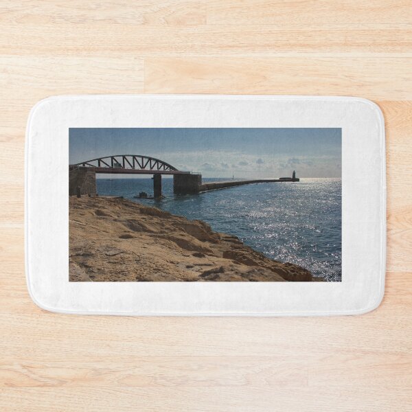 Item preview, Sunlit Rocky Coastline With Arched Bridge and Distant Lighthouse Over Sparkling Blue Sea designed and sold by Nmallia.