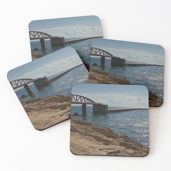 Item preview, Sunlit Rocky Coastline With Arched Bridge and Distant Lighthouse Over Sparkling Blue Sea designed and sold by Nmallia.