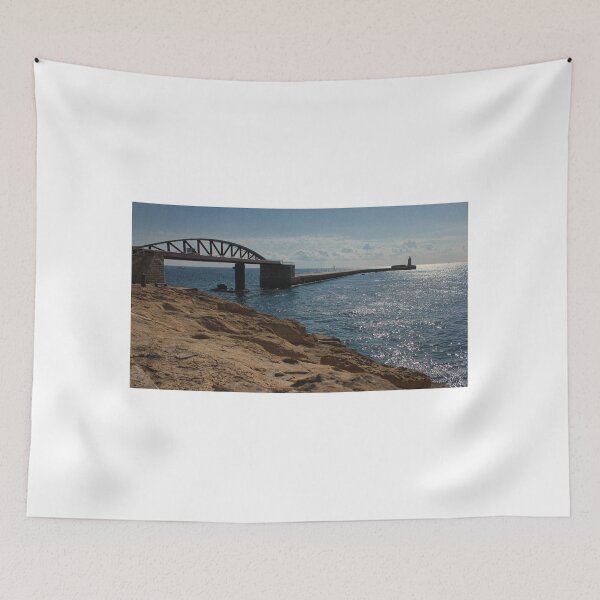 Item preview, Sunlit Rocky Coastline With Arched Bridge and Distant Lighthouse Over Sparkling Blue Sea designed and sold by Nmallia.