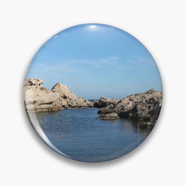 Item preview, Sunlit Rocky Coastline With Clear Blue Water and Calm Sea Under A Bright Sky designed and sold by Nmallia.