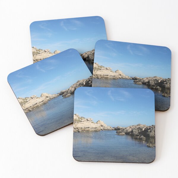 Item preview, Sunlit Rocky Coastline With Clear Blue Water and Calm Sea Under A Bright Sky designed and sold by Nmallia.