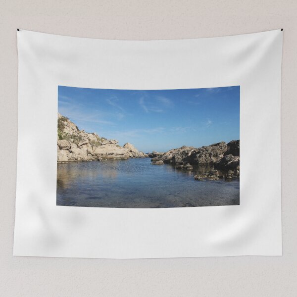 Item preview, Sunlit Rocky Coastline With Clear Blue Water and Calm Sea Under A Bright Sky designed and sold by Nmallia.