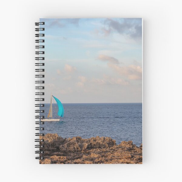 Item preview, Sailboat With Bright Blue Sail Cruising Near Rocky Shoreline Under Calm Sky And Open Horizon designed and sold by Nmallia.