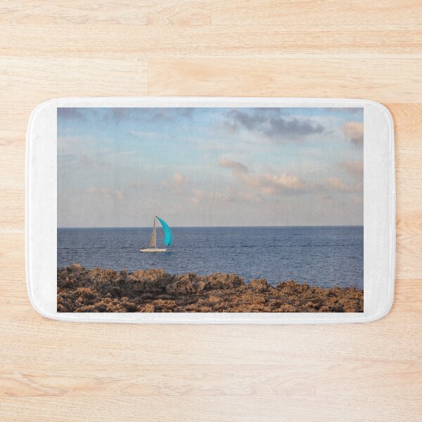 Item preview, Sailboat With Bright Blue Sail Cruising Near Rocky Shoreline Under Calm Sky And Open Horizon designed and sold by Nmallia.