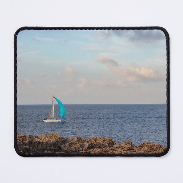 Item preview, Sailboat With Bright Blue Sail Cruising Near Rocky Shoreline Under Calm Sky And Open Horizon designed and sold by Nmallia.