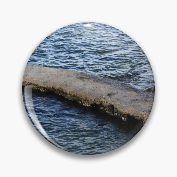 Item preview, Weathered Concrete Jetty Extending Over Rocky Shoreline Into Calm Blue Sea At Coast designed and sold by Nmallia.