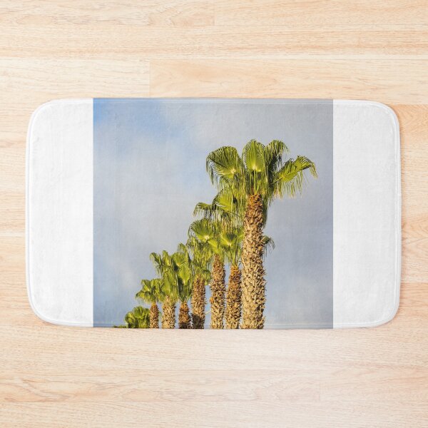 Item preview, Row of Sunlit Palm Trees Against Blue Sky With Soft Clouds in Tropical Landscape designed and sold by Nmallia.