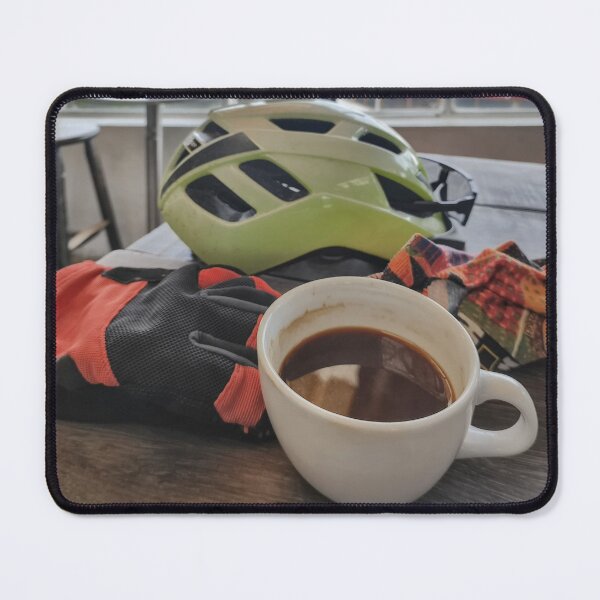 Item preview, A road cyclist taking a coffee break, wearing a helmet and gloves, and holding a cup, on a rustic wooden table. designed and sold by ElementoVisual.