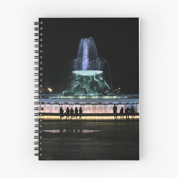 Item preview, Illuminated Night Fountain With Silhouetted People Gathered Around Water Feature in City Square designed and sold by Nmallia.