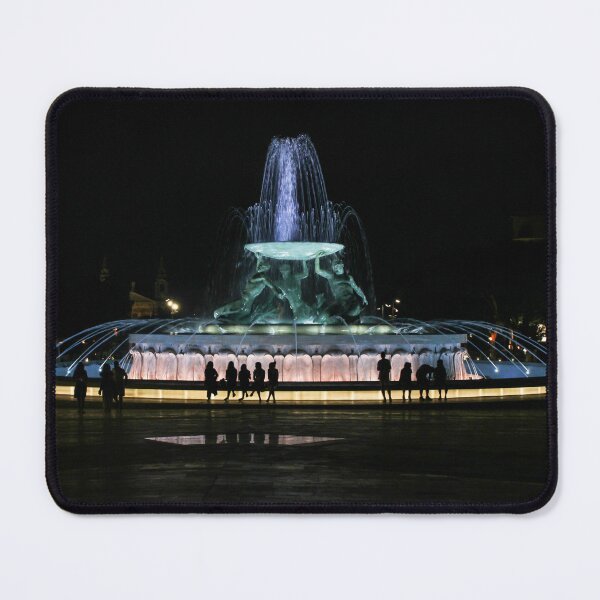 Item preview, Illuminated Night Fountain With Silhouetted People Gathered Around Water Feature in City Square designed and sold by Nmallia.
