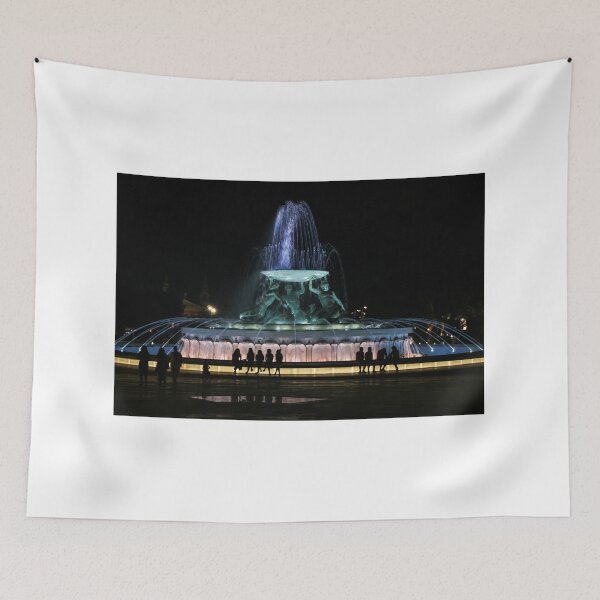 Item preview, Illuminated Night Fountain With Silhouetted People Gathered Around Water Feature in City Square designed and sold by Nmallia.