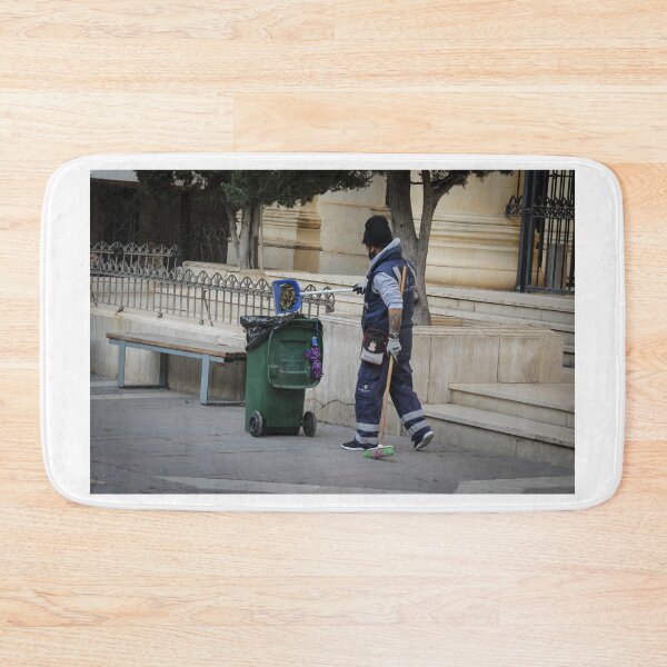 Item preview, Street Cleaner Wearing Uniform Sweeping Near Green Trash Bin by Public Steps and Bench designed and sold by Nmallia.