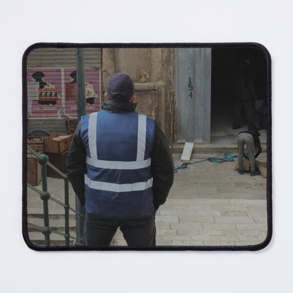 Item preview, Worker in Reflective Vest Standing on Stone Steps Outside Old Urban Building Under Renovation designed and sold by Nmallia.