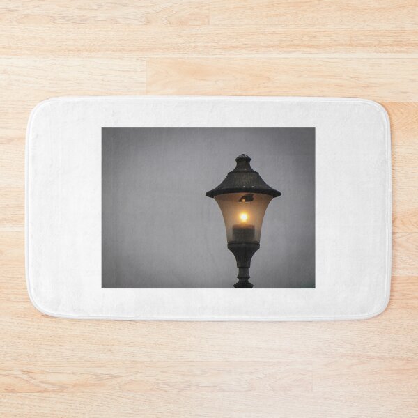 Item preview, Glowing Vintage Street Lamp at Dusk Casting Warm Light Against Overcast Sky designed and sold by Nmallia.