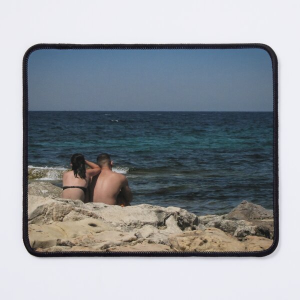 Item preview, Couple Sitting On Rocky Shoreline Looking Out At Blue Ocean Horizon On Summer Day designed and sold by Nmallia.