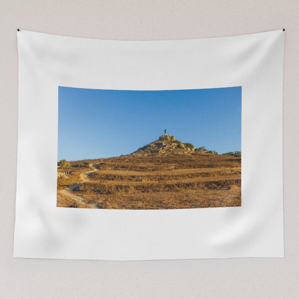 Item preview, Solitary Statue on Rocky Hill Overlooking Winding Trail Through Golden Dry Grass Under Blue Sky designed and sold by Nmallia.