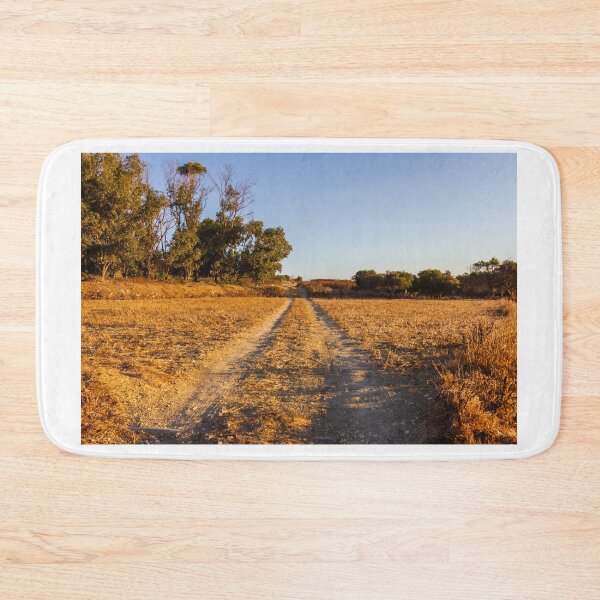 Item preview, Dirt Road Through Dry Field at Golden Hour With Trees in Rural Countryside Landscape designed and sold by Nmallia.