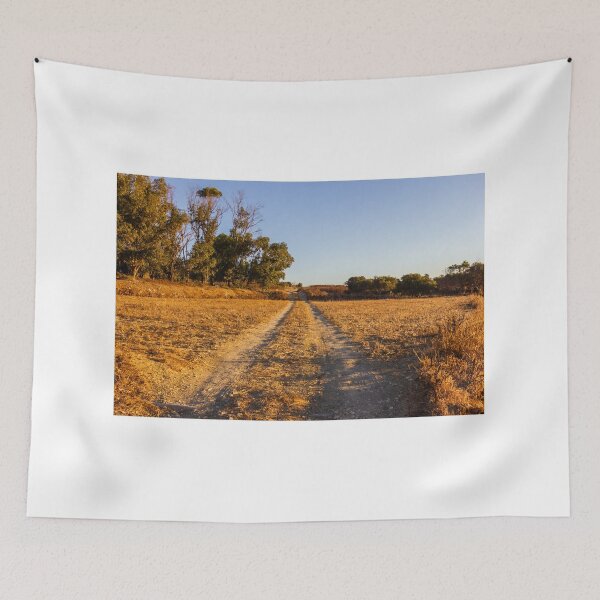 Item preview, Dirt Road Through Dry Field at Golden Hour With Trees in Rural Countryside Landscape designed and sold by Nmallia.
