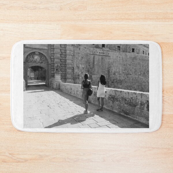 Item preview, Two Women Walking Along Historic Stone Ramparts by Ancient Arch in Mediterranean Old Town designed and sold by Nmallia.