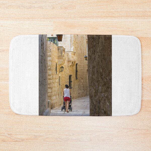 Item preview, Woman Pushing Stroller Through Narrow Historic Stone Alley in Old Town on Sunny Day designed and sold by Nmallia.