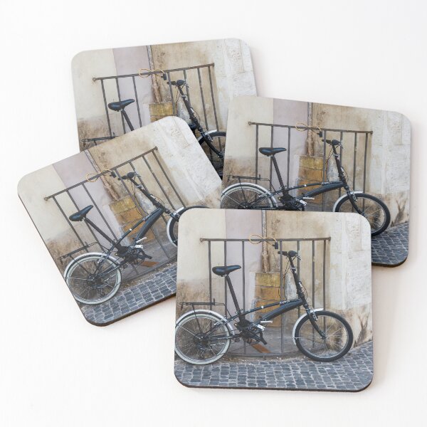 Item preview, Black Folding Bicycle Locked to Iron Rail on Cobblestone Street Beside Old Stone Wall designed and sold by Nmallia.