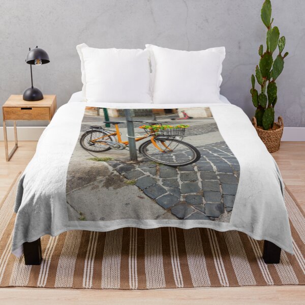 Item preview, Orange Bicycle With Flower-Filled Front Basket Locked to Pole on Cobblestone City Street designed and sold by Nmallia.