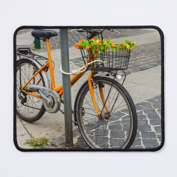 Item preview, Orange Bicycle With Flower-Filled Front Basket Locked to Pole on Cobblestone City Street designed and sold by Nmallia.