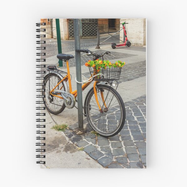 Item preview, Orange Bicycle With Flower-Filled Front Basket Locked to Pole on Cobblestone City Street designed and sold by Nmallia.