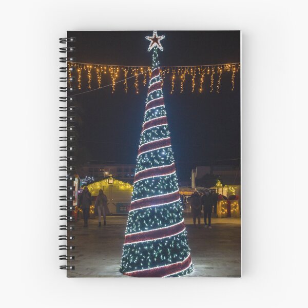 Item preview, Christmas Tree With Blue Lights In City Street At Night Surrounded By Shoppers And Festive Decorations designed and sold by Nmallia.