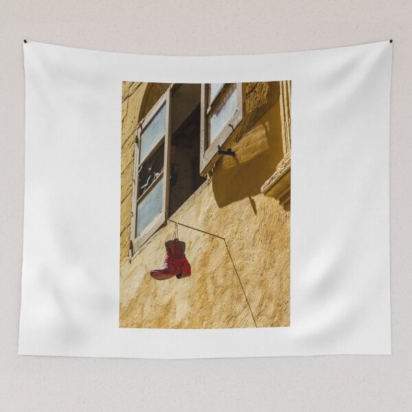 Item preview, Red Cowboy Boot Hanging From Rustic Window Above Sunlit Yellow Stucco Wall designed and sold by Nmallia.