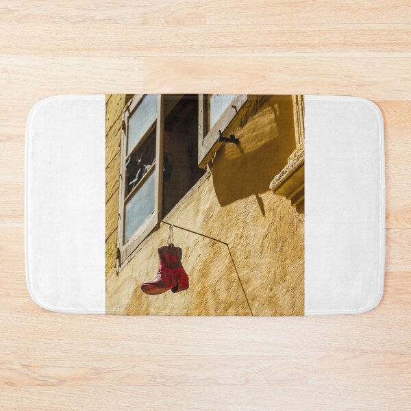 Item preview, Red Cowboy Boot Hanging From Rustic Window Above Sunlit Yellow Stucco Wall designed and sold by Nmallia.
