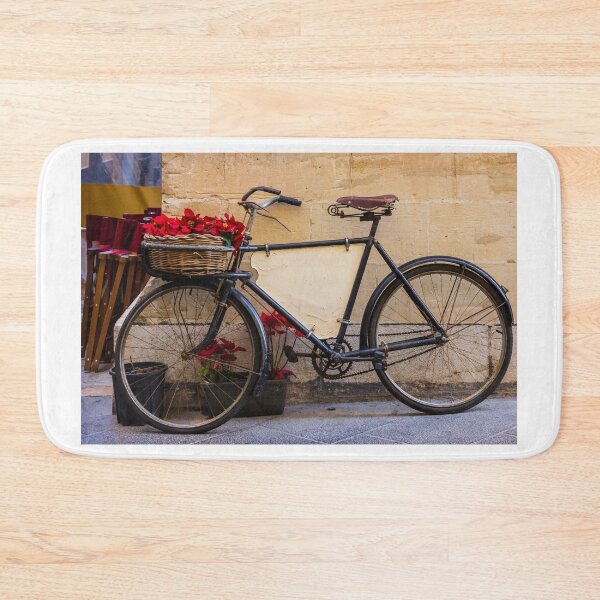 Item preview, Vintage Bicycle With Wicker Basket of Red Poinsettias Leaning Against Rustic Wall on Street designed and sold by Nmallia.