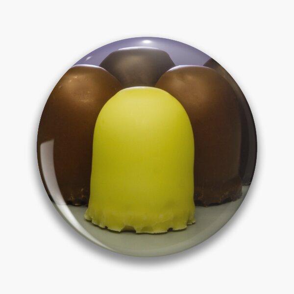 Item preview, Yellow Candy Standing Out Among Chocolate-Coated Confections On Gray Surface With Soft Lighting designed and sold by Nmallia.