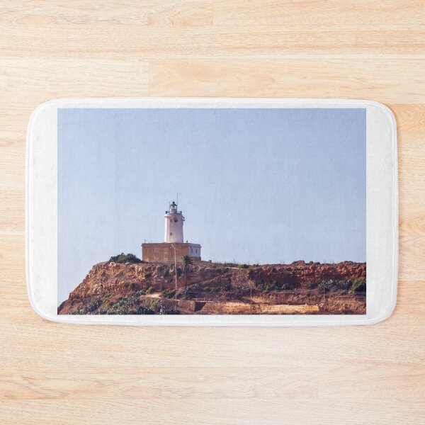 Item preview, Lonely Lighthouse Tower on Rocky Cliff Overlooking Calm Coastal Sea Under Clear Sky designed and sold by Nmallia.