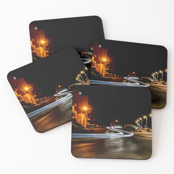 Item preview, Long Exposure Light Trails On Coastal Night Street With Lamp Posts And Parked Cars designed and sold by Nmallia.