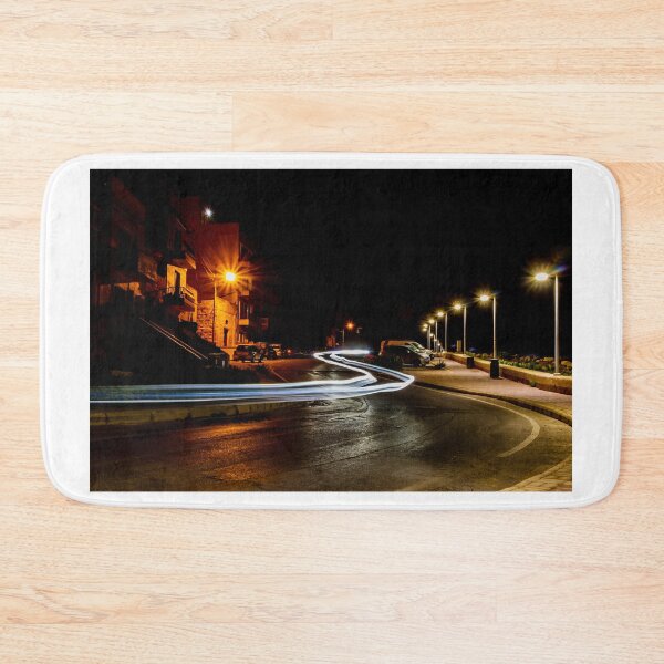 Item preview, Long Exposure Light Trails On Coastal Night Street With Lamp Posts And Parked Cars designed and sold by Nmallia.