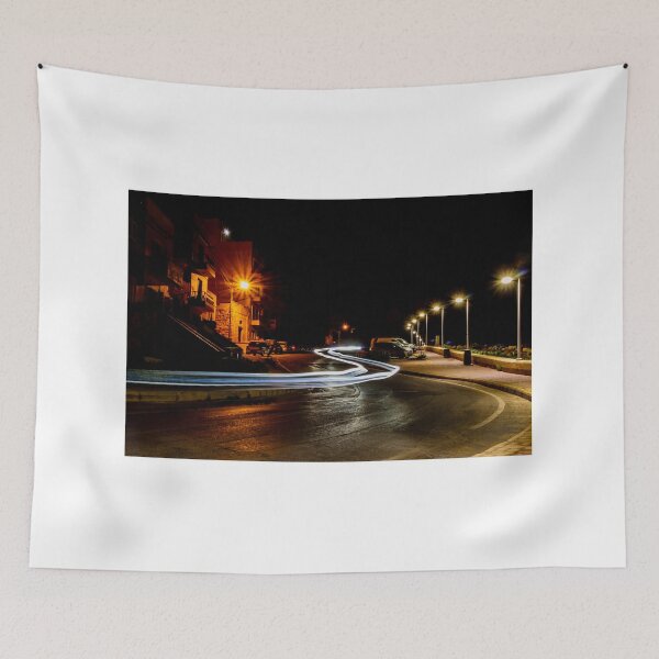 Item preview, Long Exposure Light Trails On Coastal Night Street With Lamp Posts And Parked Cars designed and sold by Nmallia.