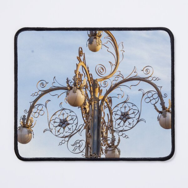 Item preview, Ornate Decorative Street Lamp With Floral Metalwork and Globe Lights Against Blue Sky designed and sold by Nmallia.