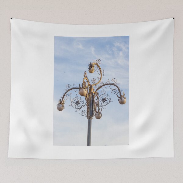Item preview, Ornate Decorative Street Lamp With Floral Metalwork and Globe Lights Against Blue Sky designed and sold by Nmallia.