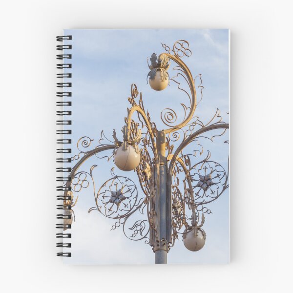 Item preview, Ornate Decorative Street Lamp With Floral Metalwork and Globe Lights Against Blue Sky designed and sold by Nmallia.