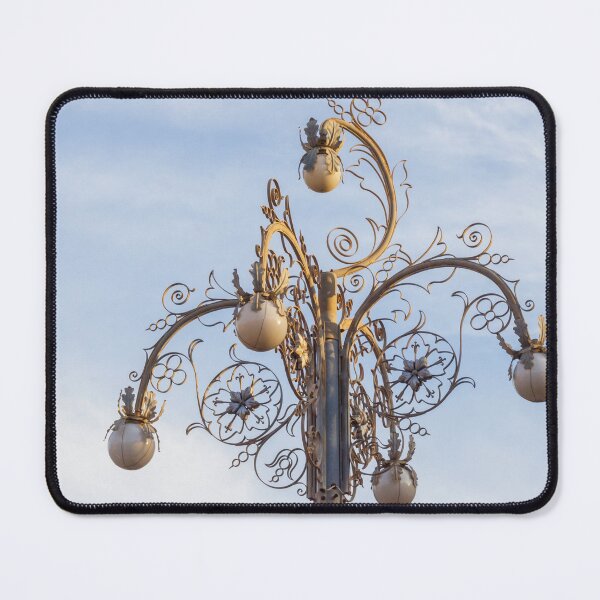 Item preview, Ornate Decorative Street Lamp With Floral Metalwork and Globe Lights Against Blue Sky designed and sold by Nmallia.