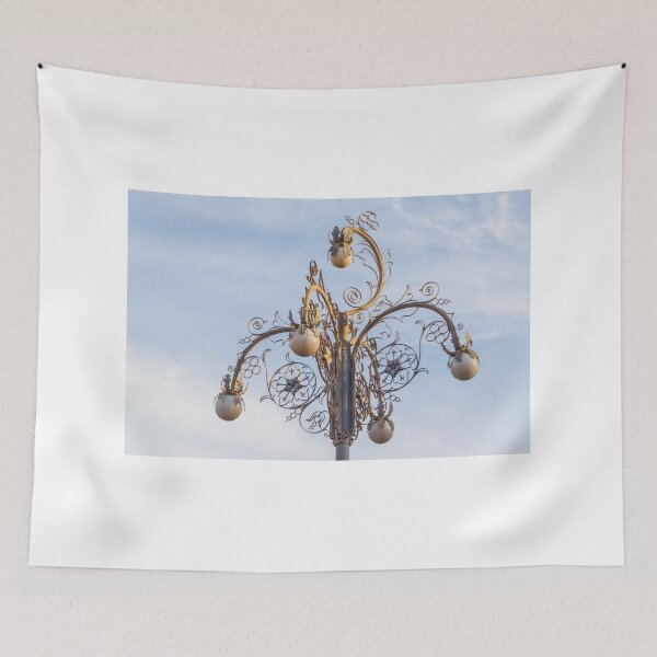Item preview, Ornate Decorative Street Lamp With Floral Metalwork and Globe Lights Against Blue Sky designed and sold by Nmallia.